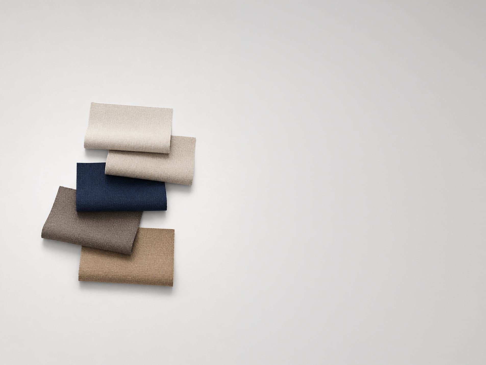 A stack of folded fabric swatches in navy, taupe, stone and ivory
